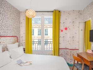 a bedroom with a bed and a window with yellow curtains at Hôtel Crayon Rouge in Paris