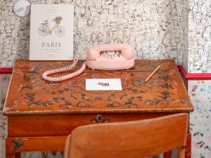 a pink telephone sitting on top of a table at Hôtel Crayon Rouge in Paris