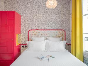 a bedroom with a red door and a white bed at Hôtel Crayon Rouge in Paris