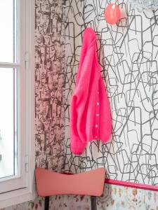 a pink towel hanging on a wall next to a chair at Hôtel Crayon Rouge in Paris