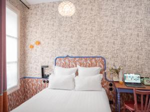 a bedroom with a bed with a blue headboard and a desk at Hôtel Crayon Rouge in Paris