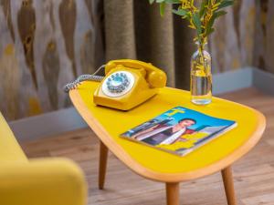 a yellow table with a phone and a vase on it at Hôtel Crayon Rouge in Paris
