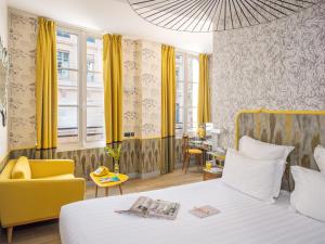 a hotel room with a bed and a yellow chair at Hôtel Crayon Rouge in Paris