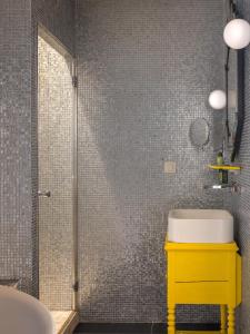a bathroom with a yellow sink and a shower at Hôtel Crayon Rouge in Paris