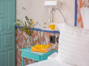 a blue table with a vase on it next to a bed at Hôtel Crayon Rouge in Paris