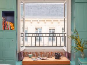 a window in a room with a wooden table in front at Hôtel Crayon Rouge in Paris
