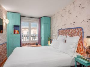 a bedroom with a white bed with a blue headboard at Hôtel Crayon Rouge in Paris