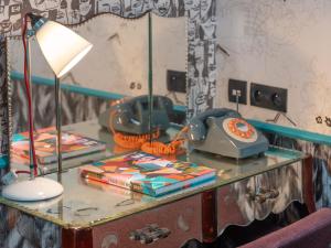 a table with a lamp and books on it at Hôtel Crayon Rouge in Paris