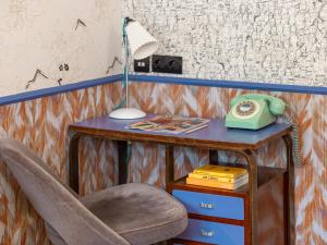 a desk with a chair and a telephone on it at Hôtel Crayon Rouge in Paris