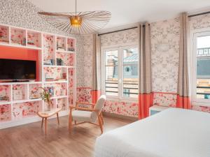 a bedroom with a bed and a tv and a chair at Hôtel Crayon Rouge in Paris