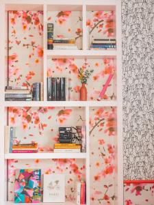 a white book shelf with books and flowers at Hôtel Crayon Rouge in Paris