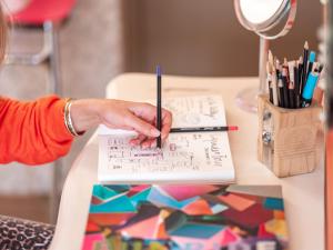 a woman writing on a paper on a table at Hôtel Crayon Rouge in Paris