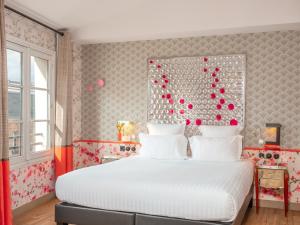 a bedroom with a white bed with red and pink decorations at Hôtel Crayon Rouge in Paris