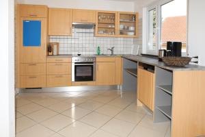 cocina con armarios de madera y suelo de baldosa en FeWo Bayha "Im Ort", en Langenargen