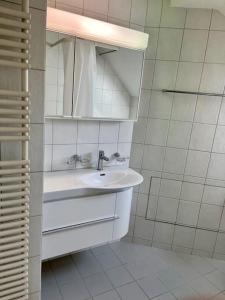 a white bathroom with a sink and a mirror at Quiet Attic-Apartment Bern Center in Bern