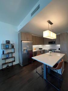 a kitchen with a table and a stainless steel refrigerator at Midtown High Rise Escape in Houston