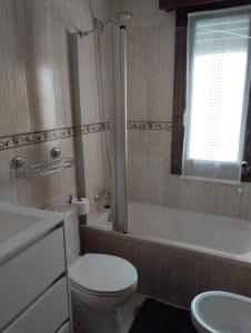 een badkamer met een toilet, een bad en een wastafel bij Apartamento Noja Beach in Noja