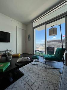 Midtown High Rise Escape في هيوستن: غرفة معيشة مع كرسي أخضر ونوافذ كبيرة
