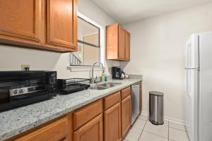 a kitchen with a sink and a refrigerator at LSU 2Bed/2Bath Angel Studios Condo *NEW* in Baton Rouge