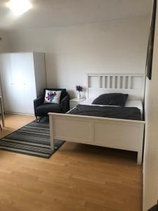 ein Schlafzimmer mit einem weißen Bett und einem Stuhl in der Unterkunft Apartment 6 am Stuttgarter Flughafen-Messe in Leinfelden-Echterdingen