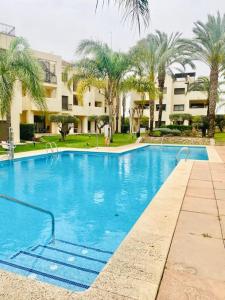 a large swimming pool with palm trees and a building at Roda Golf. Poolside apartment in Murcia
