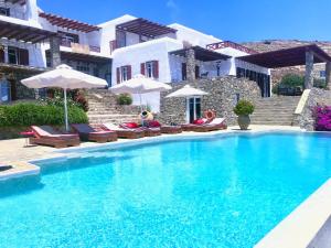 a swimming pool with chairs and umbrellas next to a house at VILLA NAUTILIA - Luxury Suites and Cottages in Kalafatis