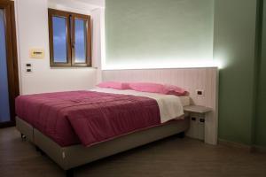 una camera da letto con un letto con cuscini rosa e una finestra di Tenuta Pietravera a Furnari