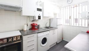 a white kitchen with a sink and a washing machine at CasaGoa in Madrid