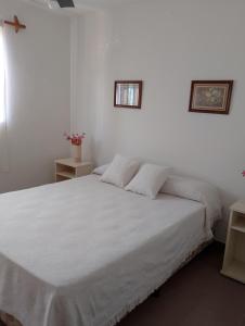 um quarto com uma cama branca e duas mesas em Mi Rincón bonito em Salta
