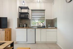 een keuken met witte kasten, een wastafel en een raam bij Apartament Fauna- blisko morza in Gdańsk