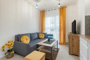 een woonkamer met een blauwe bank en een tafel bij Apartament Fauna- blisko morza in Gdańsk