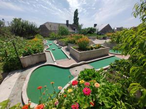 un jardín con 2 campos de minigolf y flores en Les Dépendances du Château, en Noailles