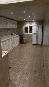 a large kitchen with white cabinets and a refrigerator at إستراحة المزرعة in Abha