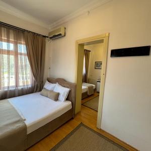 Schlafzimmer mit einem Bett und einer Tür, die in ein Zimmer führt in der Unterkunft Sözer Otel in Ayvalık