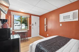 Schlafzimmer mit orangefarbenen Wänden, einem Bett und einem Tisch in der Unterkunft The Beaches Guestrooms and Cottages in Wells