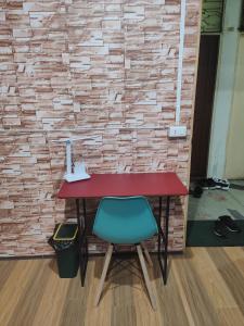 バンコクにある108 Quiet and Cozy apartment w/free Wi-Fiのレンガの壁の横に緑の椅子とデスク