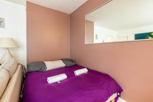 sypialnia z fioletowym łóżkiem i lustrem w obiekcie GuestReady - Tranquil Parisian Hideaway w Paryżu