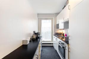 una cucina con pareti bianche e piano di lavoro nero di GuestReady - Tranquil Parisian Hideaway a Parigi