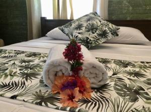 a bed with two towels and flowers on it at Ambiance Villa in La Digue