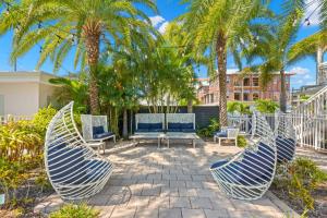 un patio con 2 sillas y palmeras en Hotel Cabana Clearwater Beach, en Clearwater Beach