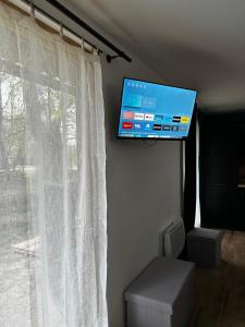 een flatscreen-tv aan een muur naast een raam bij Fromental in Saint-Côme-dʼOlt