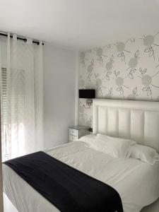 - une chambre avec un lit blanc et une couverture noire dans l'établissement Apartamentos Abril, à Nerja