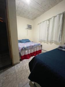 a bedroom with two beds and a window at Via sol rio das ostras in Rio das Ostras