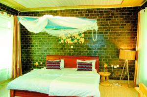 a bedroom with a bed and a brick wall at Karisimbi Cave Resort in Ruhengeri
