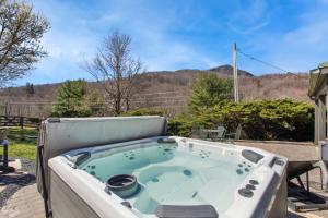 a jacuzzi tub on a patio with mountains in the background at Bluff View Farm in West Jefferson