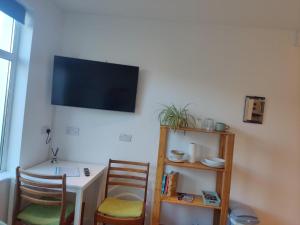 a room with a table and two chairs and a television on the wall at Garden Room in Cardigan