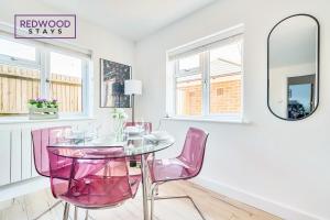 comedor con sillas rosas y mesa de cristal en Modern Serviced Apartments For Contractors & Families With FREE Parking, WiFi & Netflix By REDWOOD STAYS, en Basingstoke