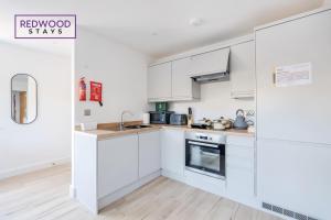 a white kitchen with white cabinets and appliances at Modern Serviced Apartments For Contractors & Families with Free Parking, WiFi & Netflix By Redwood Stays in Basingstoke
