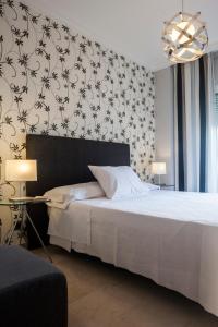 1 dormitorio con cama blanca y papel pintado en blanco y negro en Apartamentos Abril, en Nerja
