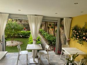 a patio with white tables and chairs and a garden at PARADISE INN in Livorno